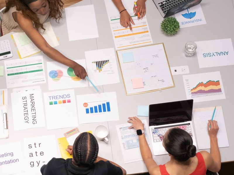 Trabajadores en una reunión de trabajo revisando información, gráficos, cuadros de Excel